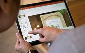 Image of a tablet with a a mans hands navigating on the screen.