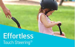 Image of an adults hand controlling a SmarTrike trike with a child in it.