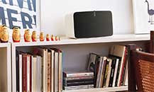 Image of a Sonos speaker placed on top of a bookcase.