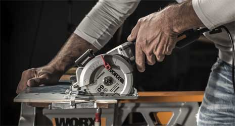 Image of a man using a circular saw to cut a piece of wood on a work bench.