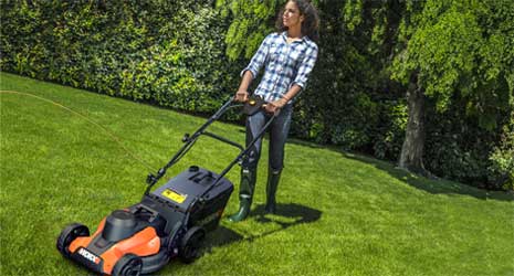 Image of a woman mowing a large lawn with a WORX lawnmower.